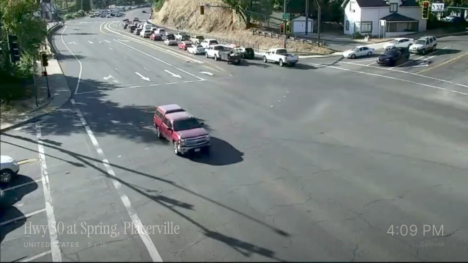 Pantalla completa de una cámara de autopista en California, un coche rojo en el cruce, el nombre del lugar y la hora local abajo