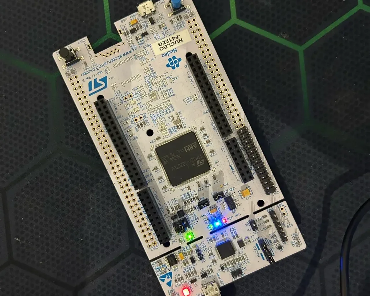 The NUCLEO-F412ZG board plugged in over USB, its green, blue and red LEDs lit.